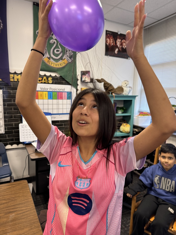 A student observes how static electricity from a balloon pulls her hair