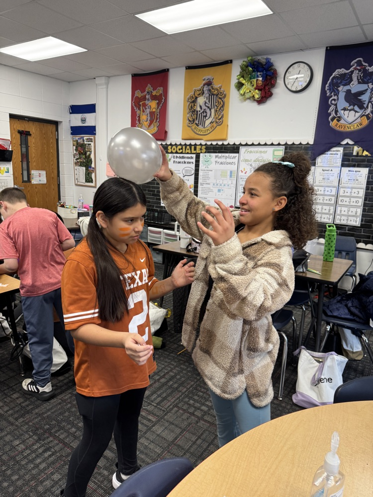 A student rubs a balloon on a classmate’s head to observe electron transfer