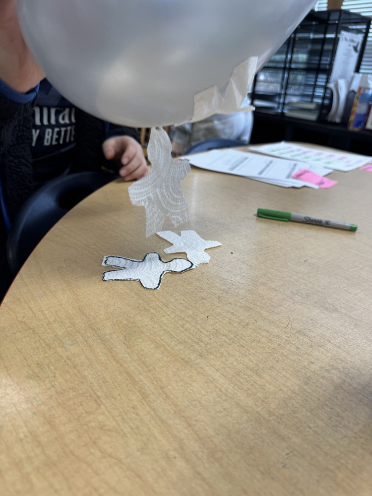 A balloon pulls tiny pieces of paper through static charge 