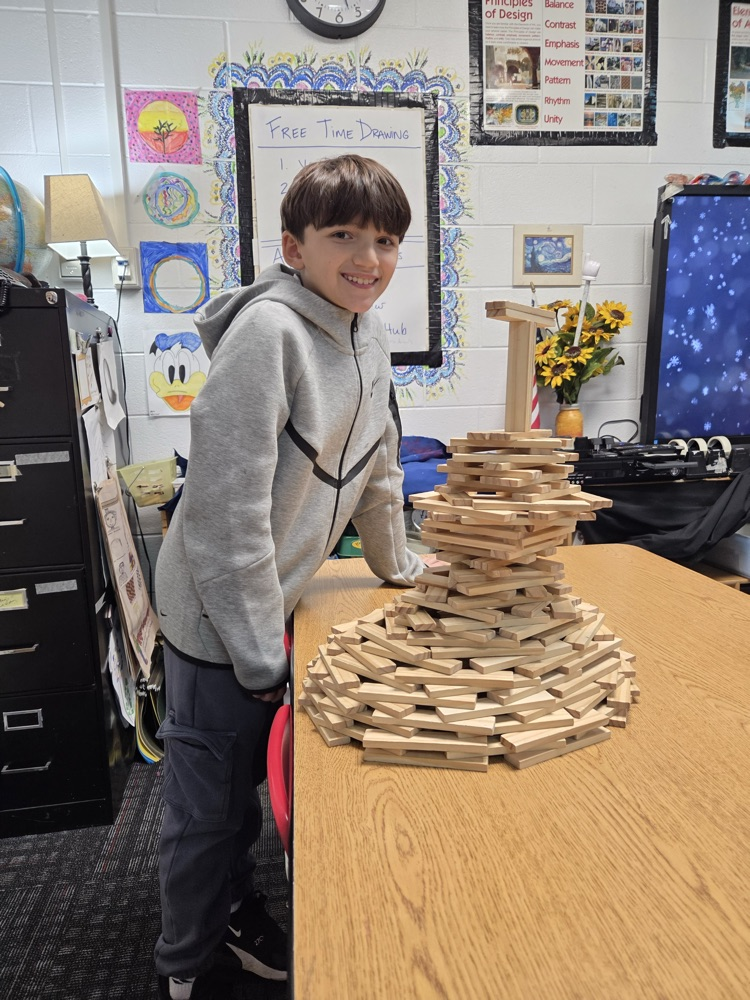 Student displaying a sculpture he did with wood blocks 