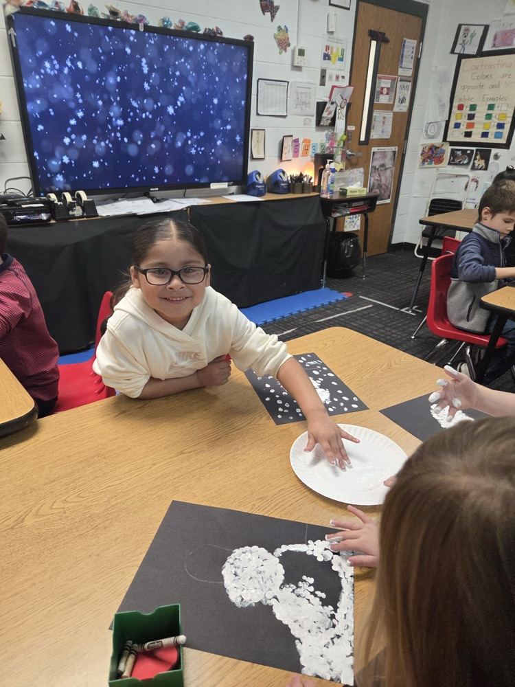 A students painting a snowmen with her fingers 