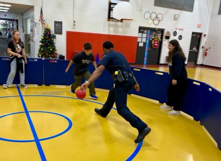 Officer Johnson playing with students in the gym  