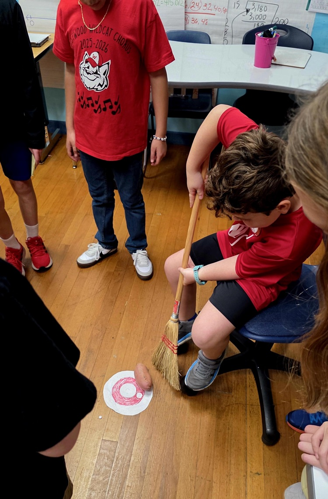 A second grader doing curling with a potato and a broom