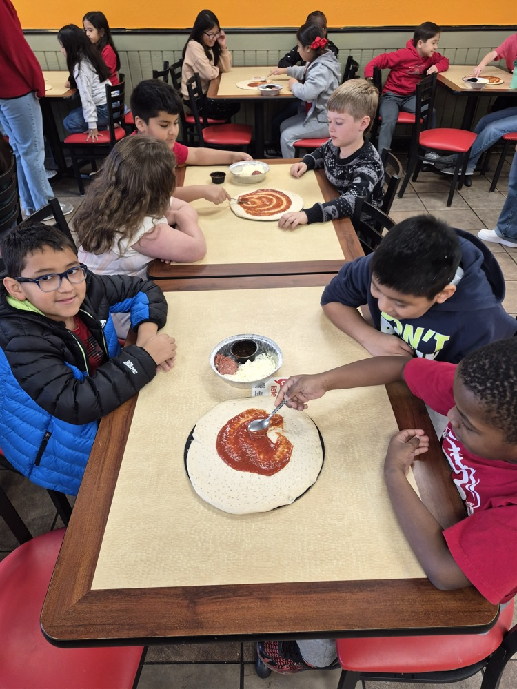 Students putting tomatoes sauce on the pizza crust 