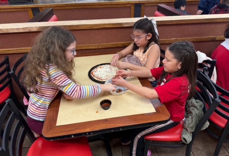 Students putting cheese in the pizza crust