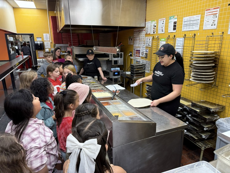 A CiCi’s employee showing the students how to make a pizza 
