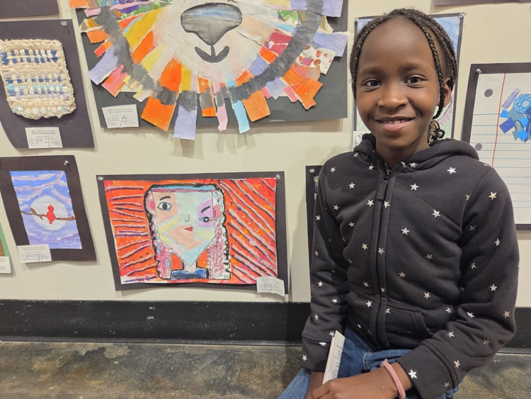 Student taking a picture with her artwork 