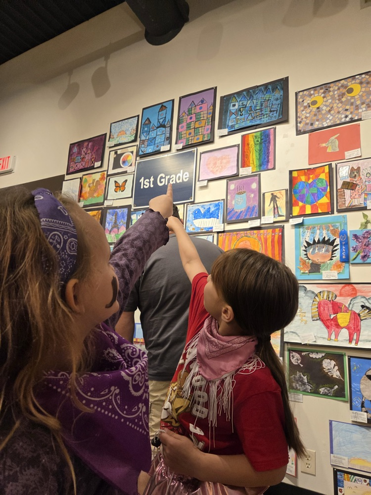 Students pointing at 1st grade artwork sign 
