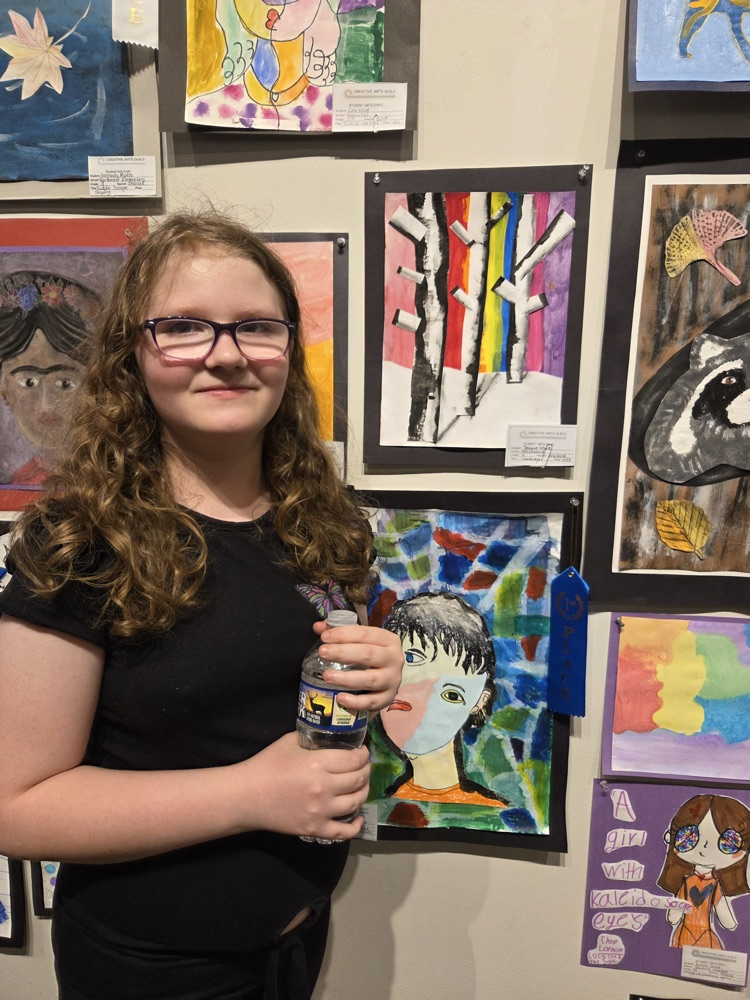 Student taking a picture with her artwork 