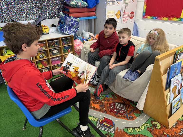 Student reading to younger students 