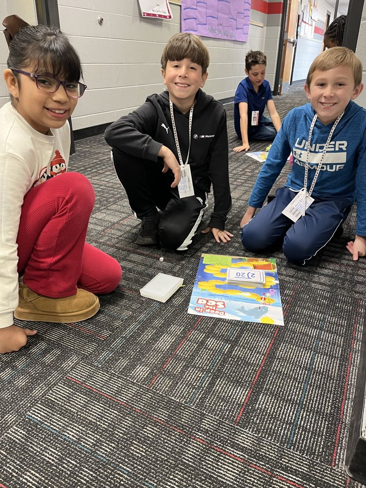 Students playing a math game with another a second grader  