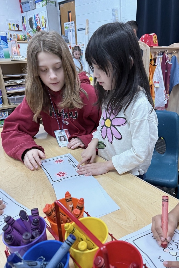 Student helping a younger student to read 