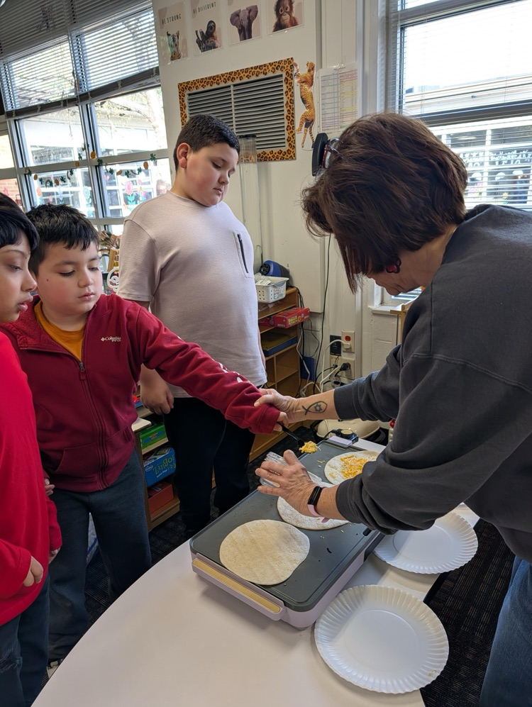 Stidents putting cheese on a tortilla to make quesadilla