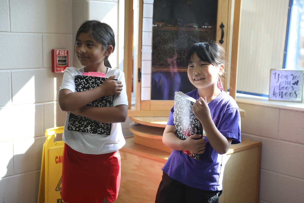 Two students hold their notebooks.