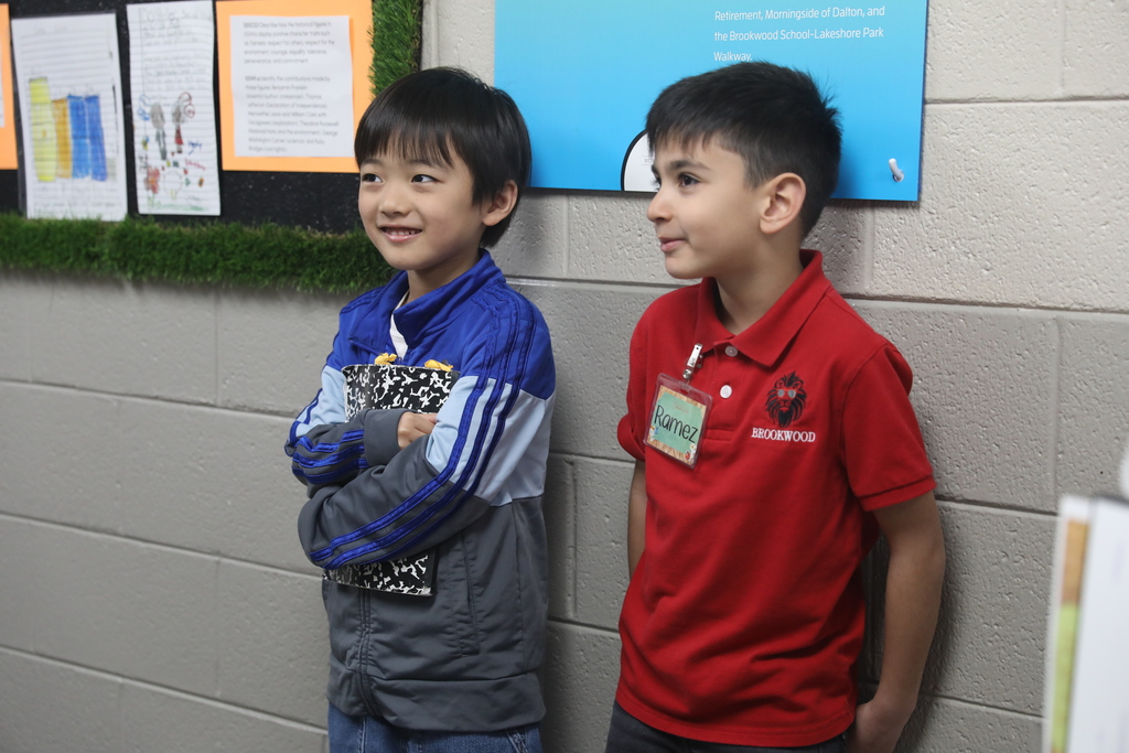 Two students standing against a wall decorated in STEM materials.