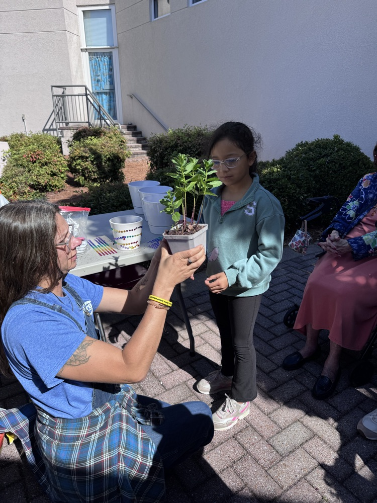 Teacher talking to a student about a plant 