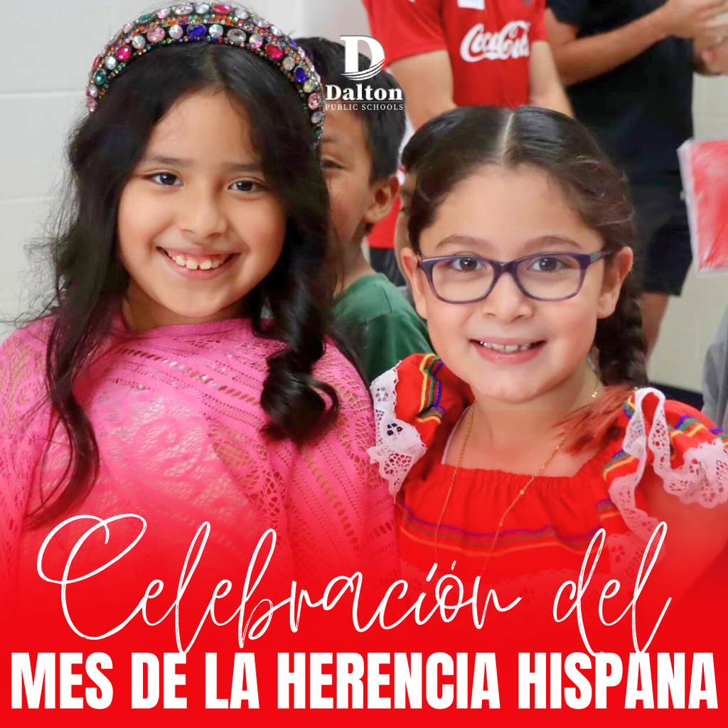 Two smiling young girls stand together at school, one wearing a pink top and jeweled headband and the other wearing glasses and a colorful traditional-style dress. Overlaid Spanish text reads “Celebración del Mes de la Herencia Hispana,” with the Dalton Public Schools logo above.