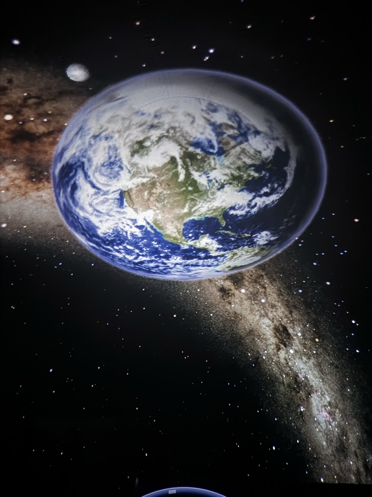 Students inside the Star Lab looking up to a picture of planet Earth, stars and constellation 