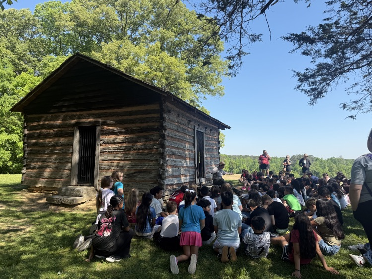 Students gathering around an old cabin on open ground fields listening to the instructor talking about the story of the Chickamauga battle 