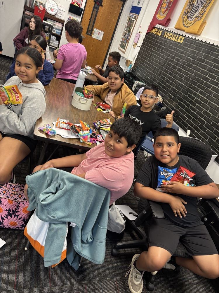 A group of students sitting on their desks showing all their prizes from the raffle 