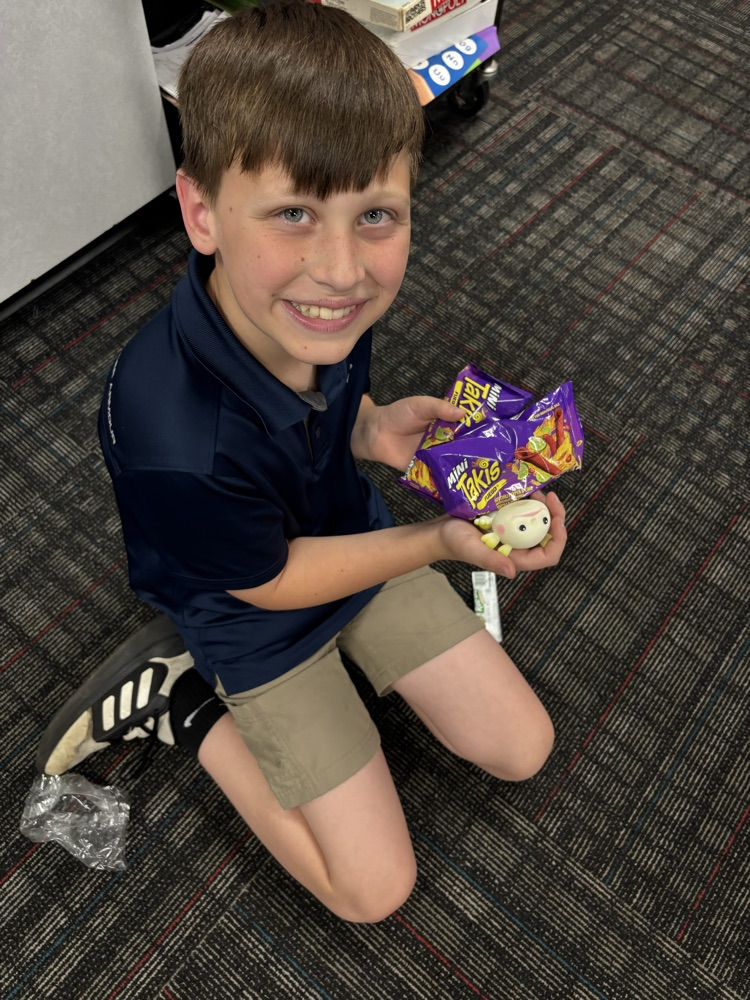A student sitting on the floor with his prizes 