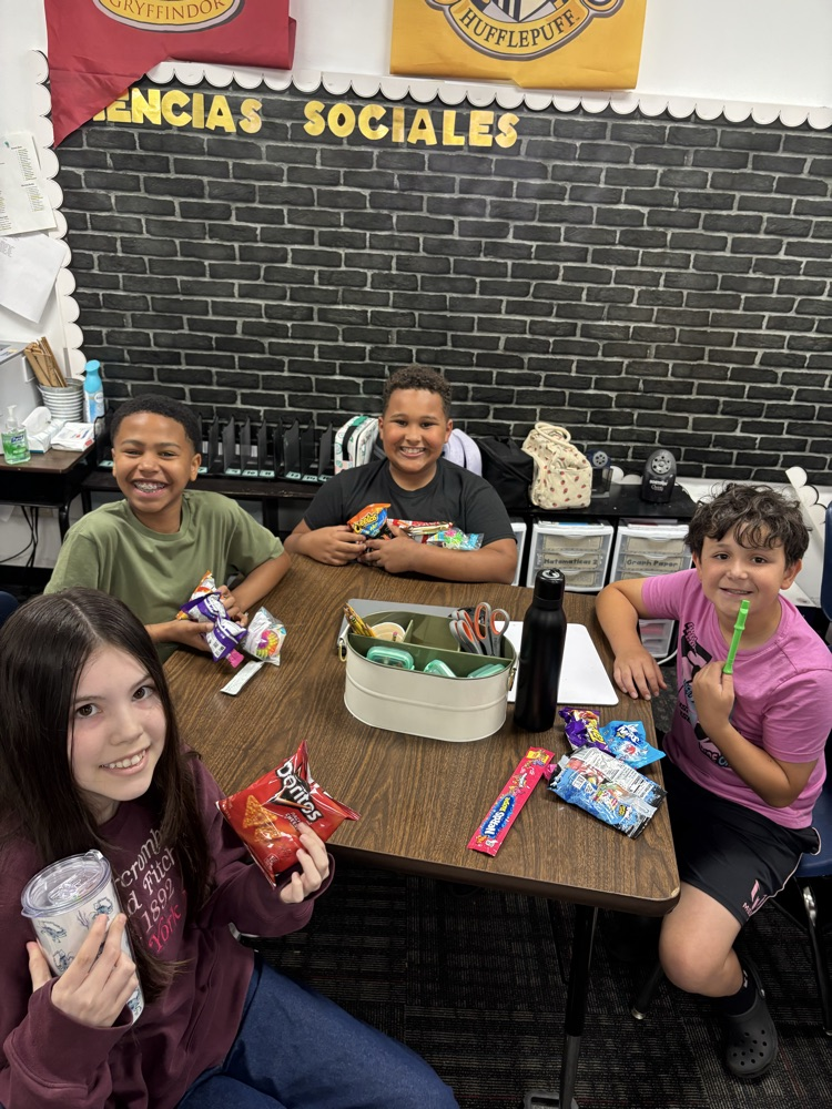 A group of students sitting on their desks with all their prizes from the raffle  