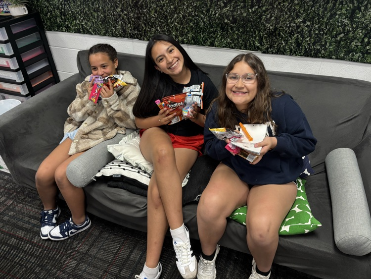 Three girls sitting on a couch holding their prizes from the raffle 