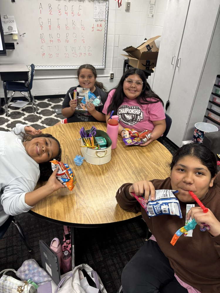 Students sitting on their desk holding their prizes from the raffle 