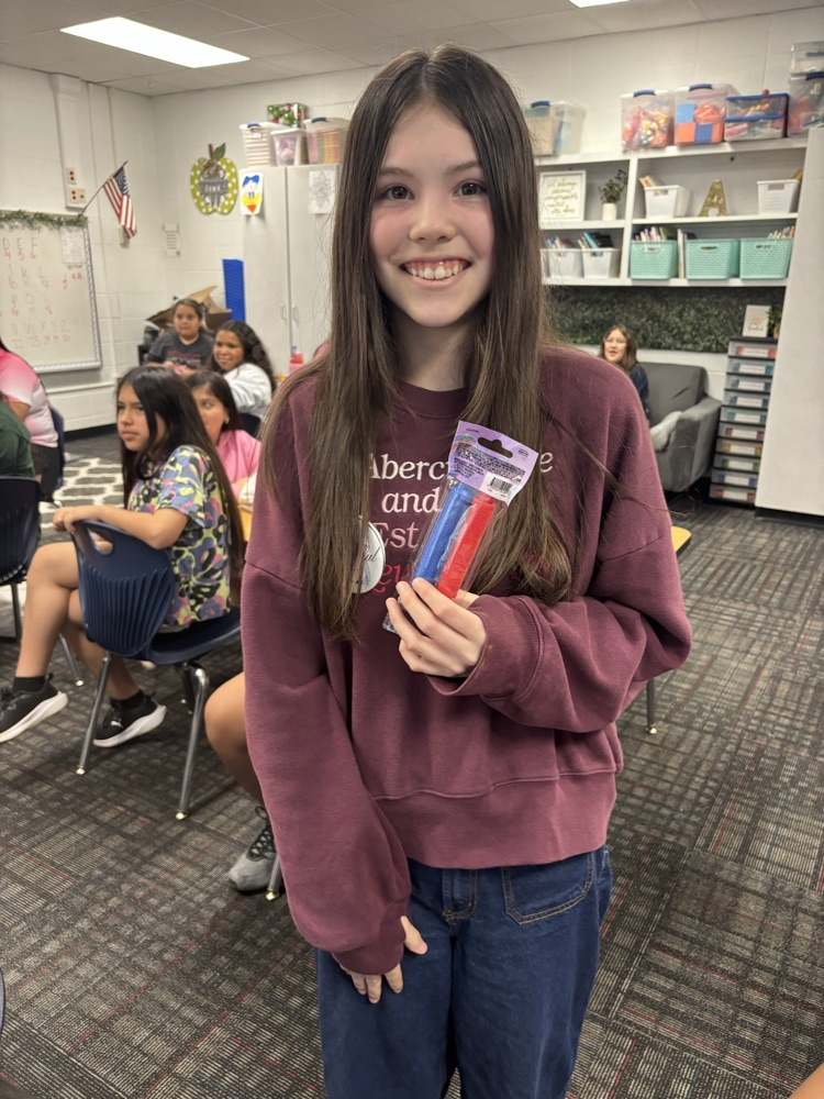 A student standing showing her prizes from the raffle 