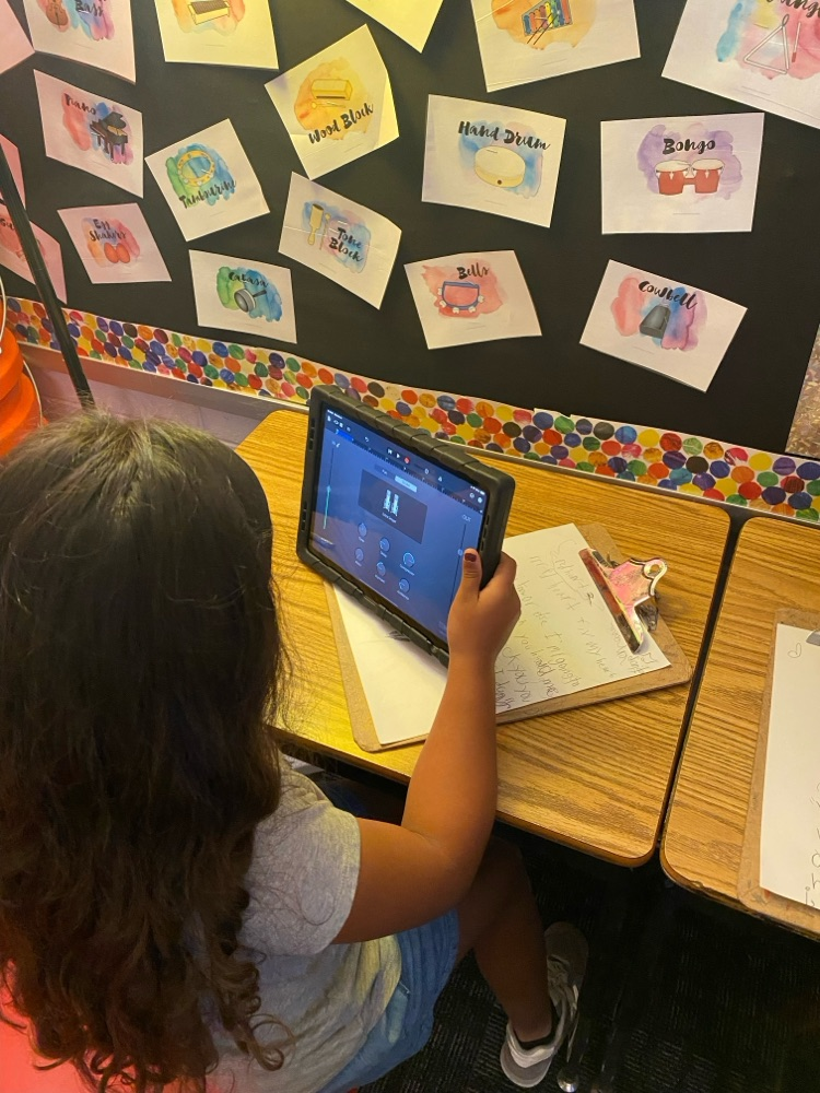 A students siting on her desk holding and looking at her iPad 