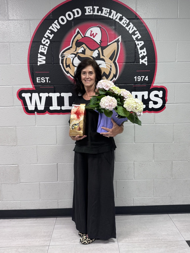 Nurse Kathy standing in front of a WW sign holding her flowers and chocolates for Nurses week