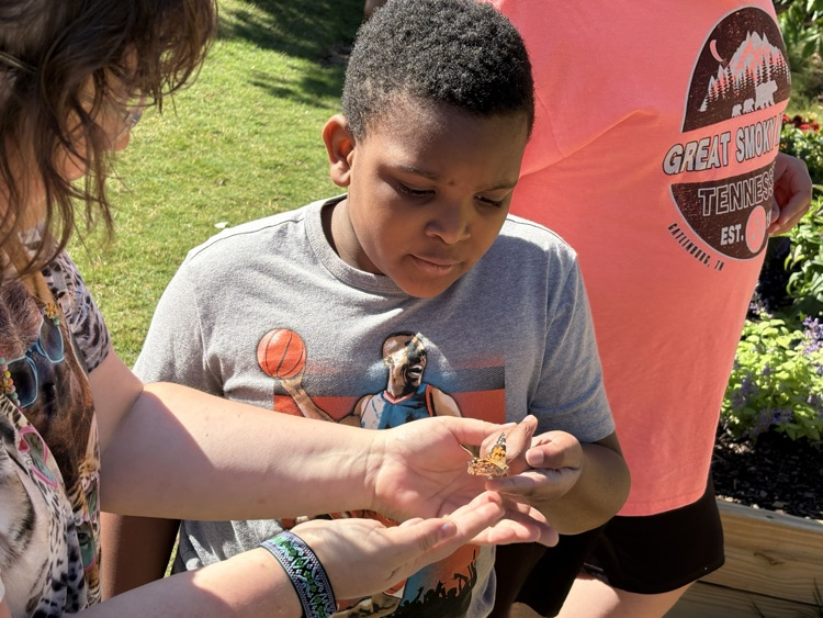 A teacher putting a butterfly on a student’s finger  