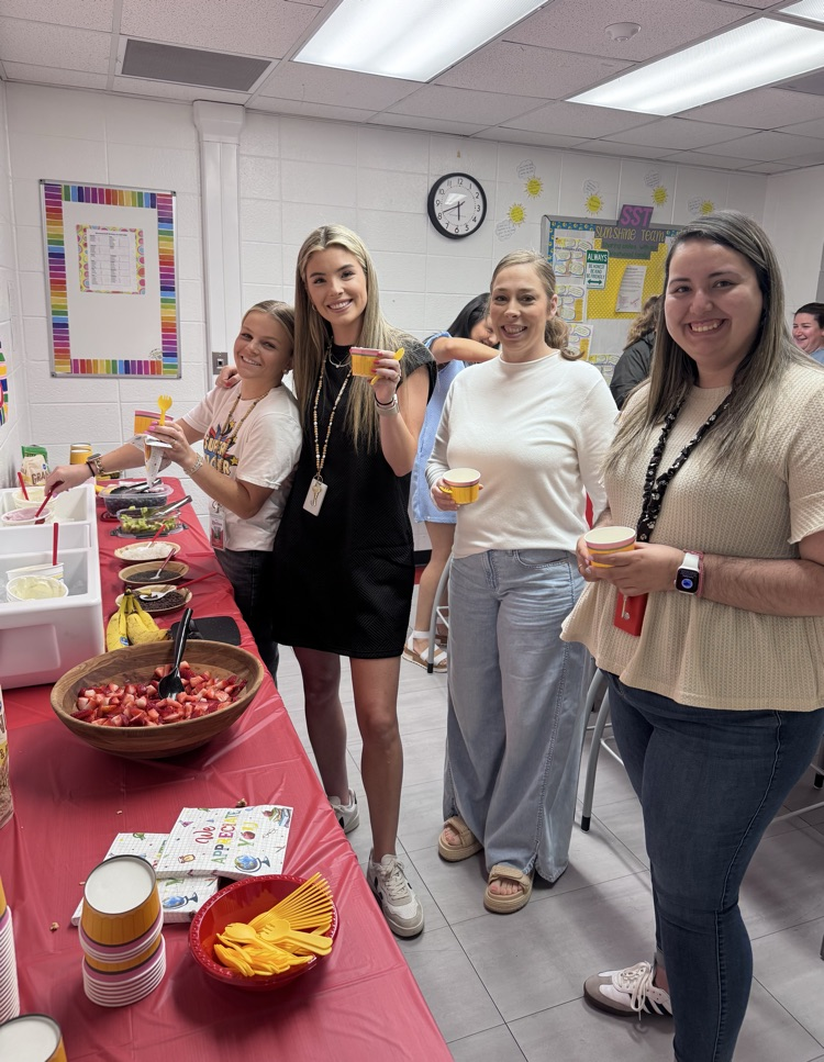 Four teachers in the teachers lounge holding their yogurt cups from the yogurt bar provided by PTO