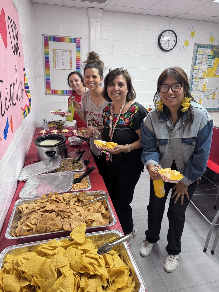 Four teachers fixing their lunch from the nacho bar provided by PTO