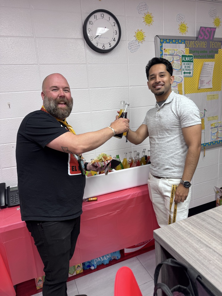 Two teachers in the teacher lounge holding their drinks 