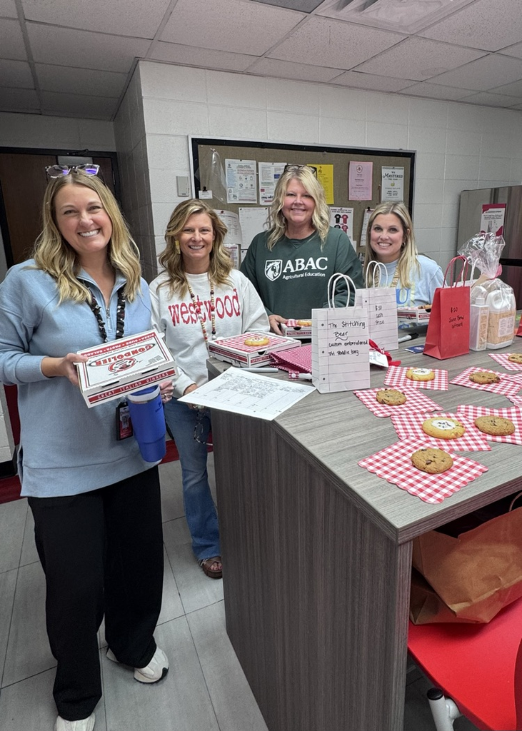 Four teachers in the teachers lounge holding their pizzas provided by PTO