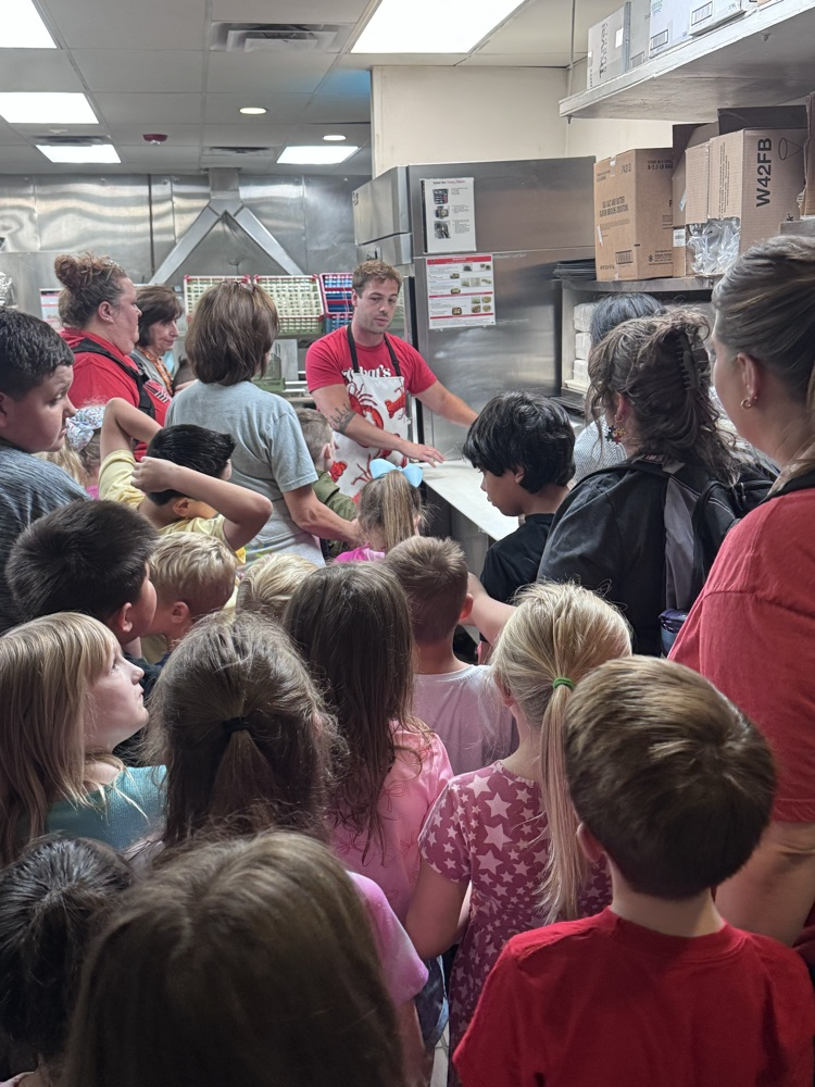 A group of students and teachers in the kitchen learning about the equipment 