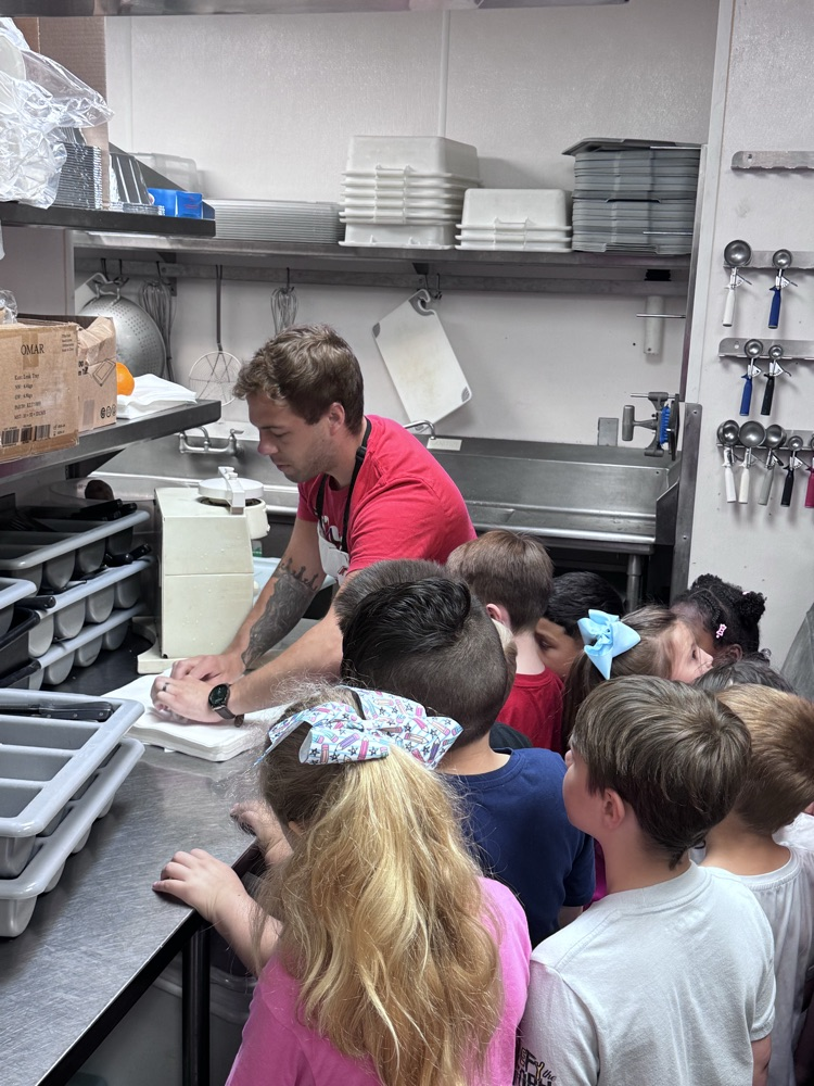 An employer showing the students how to roll the utensils in the napkins 