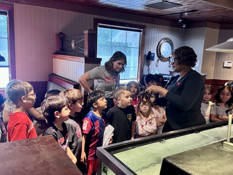 An employee holding and showing the lobster to students while they learn facts about lobsters