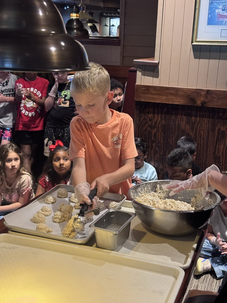A student scooping the dough from a bowl and placing it on a tray to make biscuits 