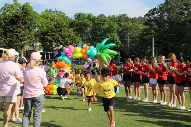 Students walking to the field through an arch of ballon’s and teachers cheering them up  