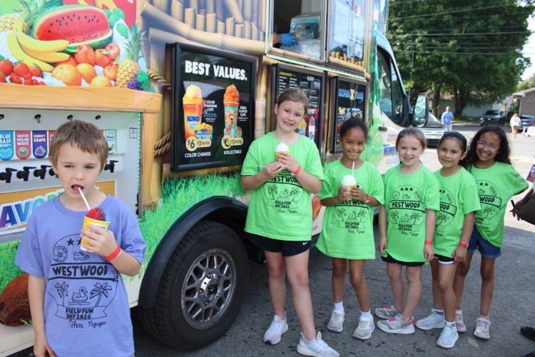 A group of students standing in front of the Kona Ice cart with their shave iced cones 