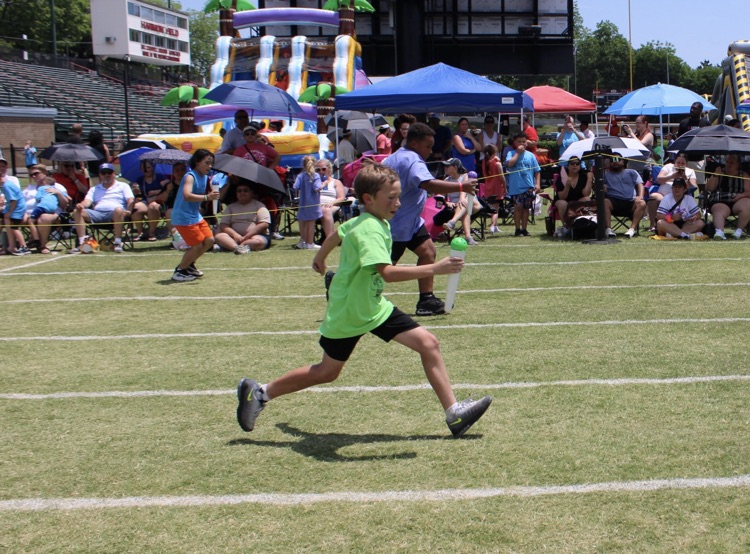 Students racing each other while holding a home with a ball on top