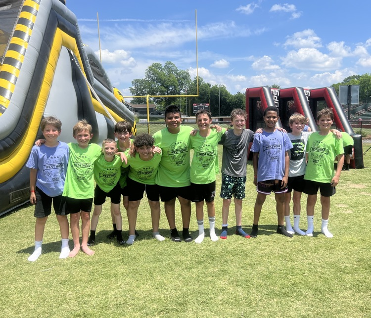 A group of fifth grade boys standing on the field in front of the inflatables