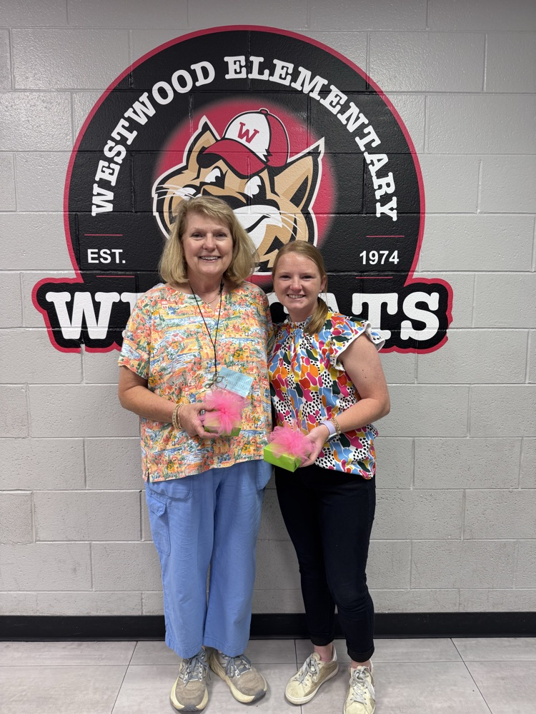 Mrs. Anderson and Mrs. Crane holding their presents in front of the Westwood mural 
