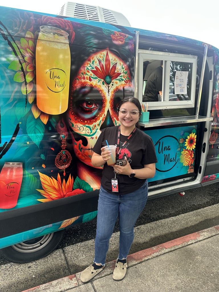 Lady holding a drink next to a truck that says Una Mas