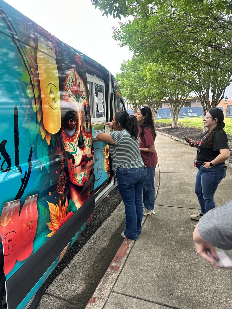 Lady holding a drink next to a truck that says Una Mas