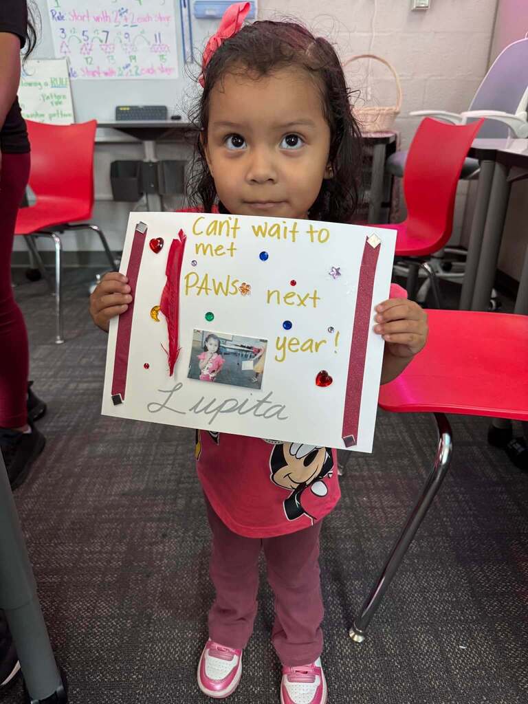 Student holding poster of paws
