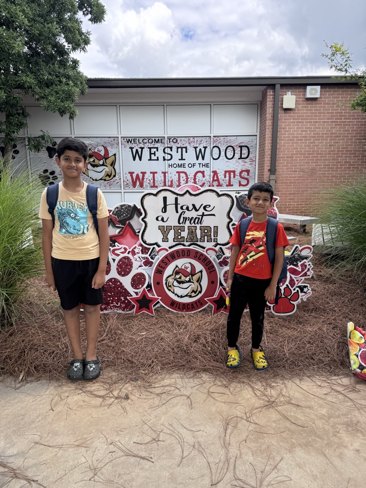 Two students standing outside in front of the yard sign that says have a great year 