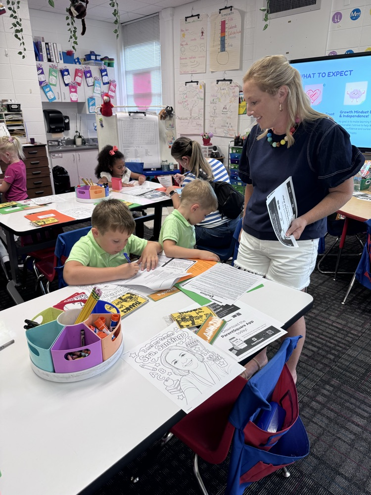 A parent standing next to her son while he’s coloring 